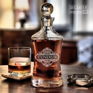 Hourglass Whiskey Decanter | Onyx 18 Personalized Hourglass crystal whiskey decanter with custom engraved Onyx reserve medallion design, shown with matching whiskey glass.